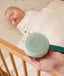 A hand holds a mint green white noise machine labeled 
