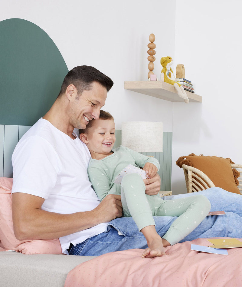 Preschooler and dad reading ergoPouch Hello, Sleep! Bedtime Affirmations for Kids in bed