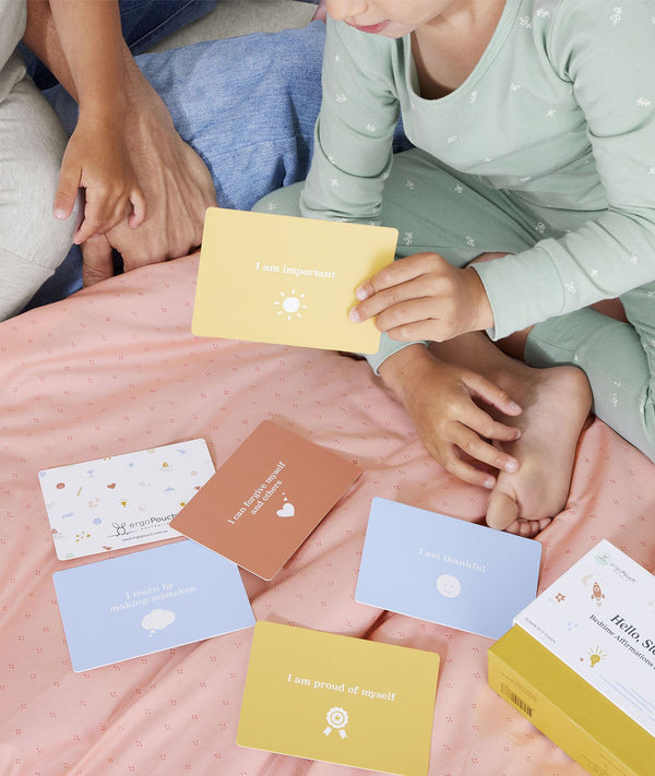 ergoPouch Hello, Sleep! Bedtime Affirmations for Kids cards scattered on bed