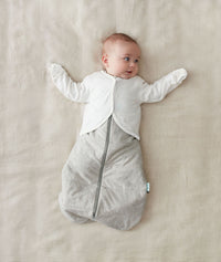 Infant lying with arms up in a winter ergoPouch Sleeping Sack with the added layer of Arm Warmers