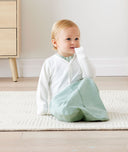Baby sitting in an everyday ergoPouch Sleeping Sack with the added layer of Arm Warmers