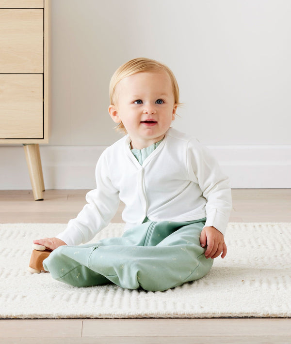 Baby sitting in an everyday ergoPouch Sleeping Sack with the added layer of Arm Warmers