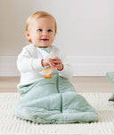 Baby sitting in an winter ergoPouch Sleeping Sack with the added layer of Arm Warmers