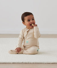Infant sitting in ergoPouch Long Sleeve Romper 1.0 TOG Vanilla