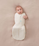 Baby wearing a ergoPouch Cocoon Swaddle Sack 1.0 TOG Oatmeal Marle, transitioning to arms out sleeping