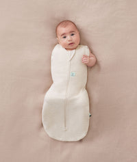 Baby wearing a ergoPouch Cocoon Swaddle Sack 1.0 TOG Oatmeal Marle, transitioning to arms out sleeping