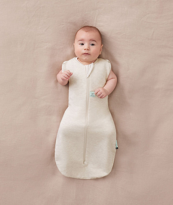 Baby sleeping with arms out in a ergoPouch Cocoon Swaddle Sack 0.2 TOG Oatmeal Marle