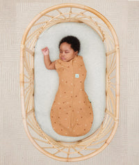 Newborn wearing ergoPouch Cocoon Swaddle Sack 0.2 TOG Honey Bees, transitioning to arms out sleeping