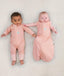 Two newborns lying wearing ergoPouch Long Sleeve Romper 1.0 TOG Berries and Cocoon Swaddle Sack 1.0 TOG Berries