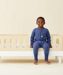 A cosy child smiling wearing a ergoPouch Sleep Onesie 2.5 TOG Night Sky