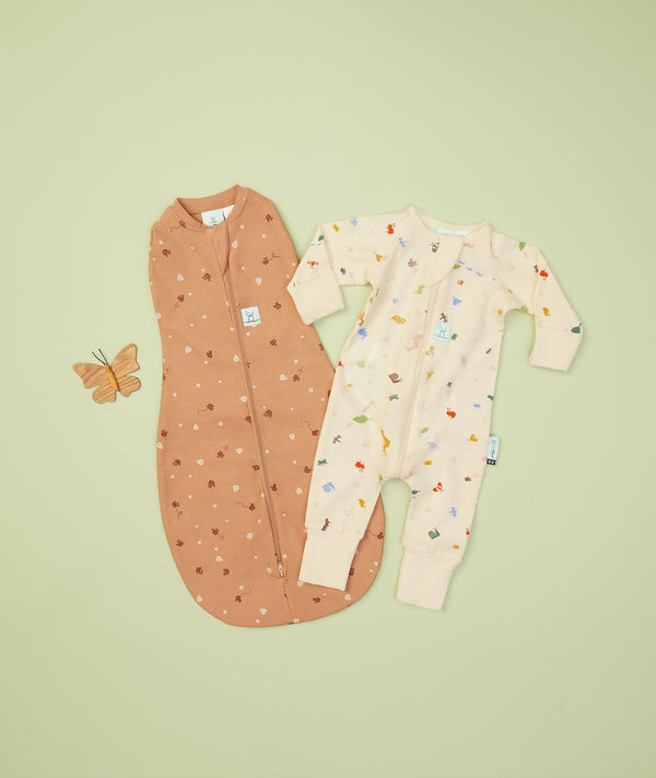 Flatlay of ergoPouch Long Sleeve Romper 0.2 TOG Critters and Cocoon Swaddle 0.2 TOG Honey Bees