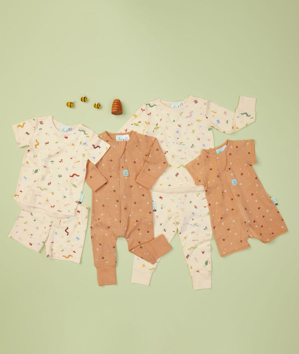 Flaylay of the ergoPouch Garden Party Collection layering, including ergoPouch Long Sleeve Romper and Pajamas in Honey Bees and Critters
