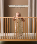 Infant standing inside the ergoPouch ellska Skye Crib, made from non-toxic beechwood to be safe from curious hands and mouths.