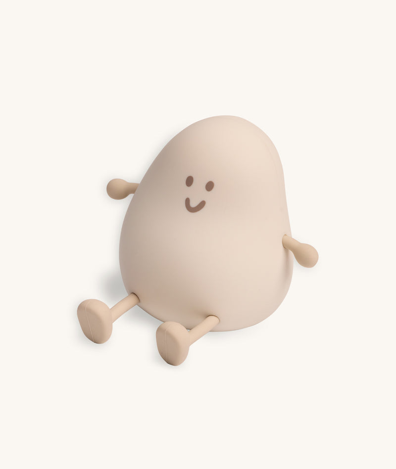 Soft-touch silicone bedtime lamp in the shape of a rounded character with a smiling face, small arms, and legs, sitting against a plain light background.