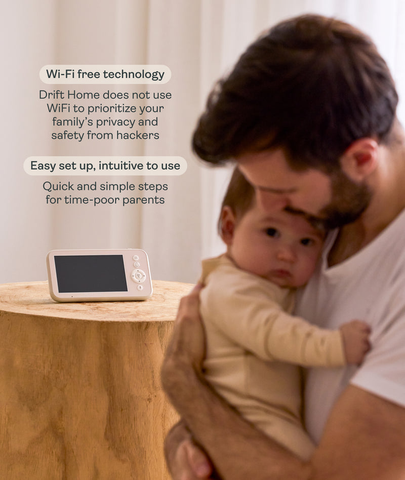 Man holding a child next to the ergoPouch Drift Home Baby Monitor and Smart TOG Guide that uses Wi-Fi-free technology to prioritize family privacy