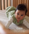 Baby lying on stomach in the ergoPouch ellska Skye Crib with an open side, providing breathability, safety, and clear sight-lines from every angle.