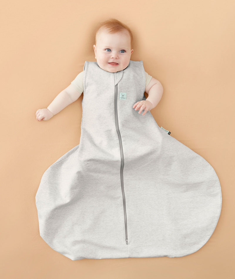 Smiling baby wearing with hip dysplasia wearing a ergoPouch Hip Harness Sleep Sack 1.0 TOG Grey Marle