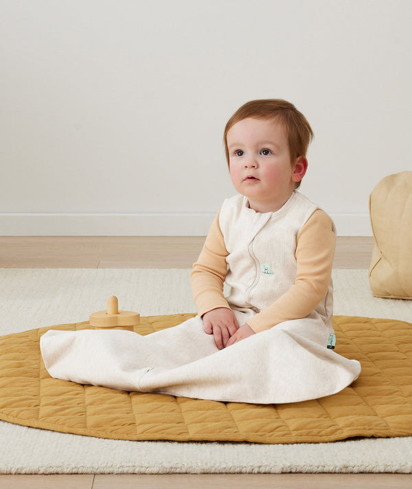 Child sitting up in a Hip Harness Sleep Sack 0.2 TOG Oatmeal Marle