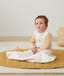 Child sitting up in a Hip Harness Sleep Sack 0.2 TOG Oatmeal Marle