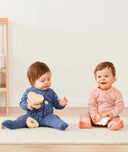 Two babies sitting wearing ergoPouch Long Sleeve Romper 1.0 TOG Night Sky and Berries