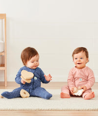 Two babies sitting wearing ergoPouch Long Sleeve Romper 1.0 TOG Night Sky and Berries