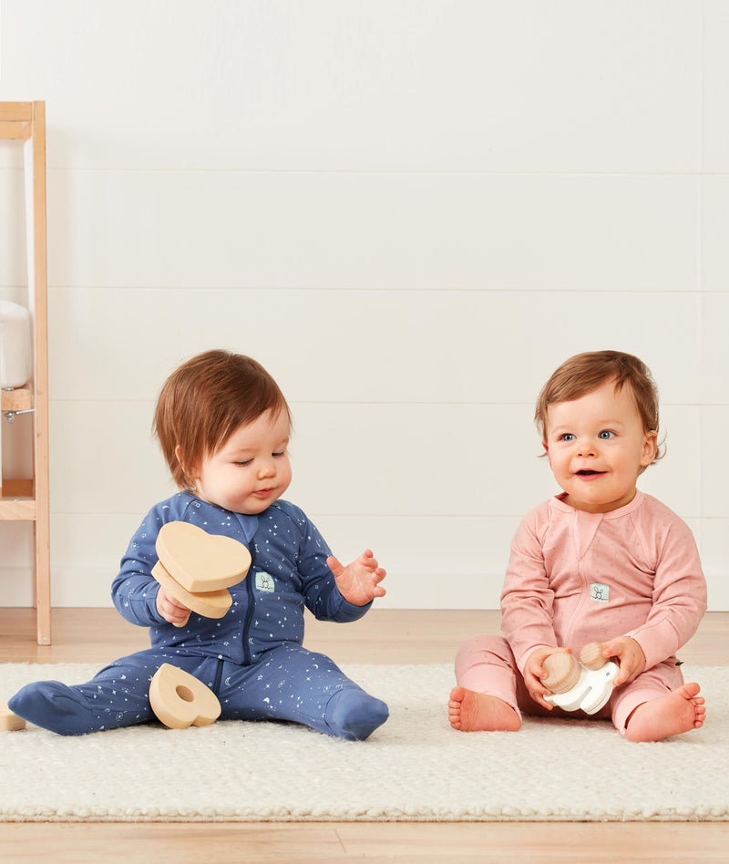 Two babies sitting wearing ergoPouch Long Sleeve Romper 1.0 TOG Night Sky and Berries