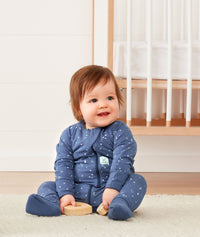 Infant sitting wearing ergoPouch Long Sleeve Romper 1.0 TOG Night Sky