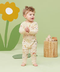 Baby standing, wearing an ergoPouch Long Sleeve Romper 0.2 TOG Critters