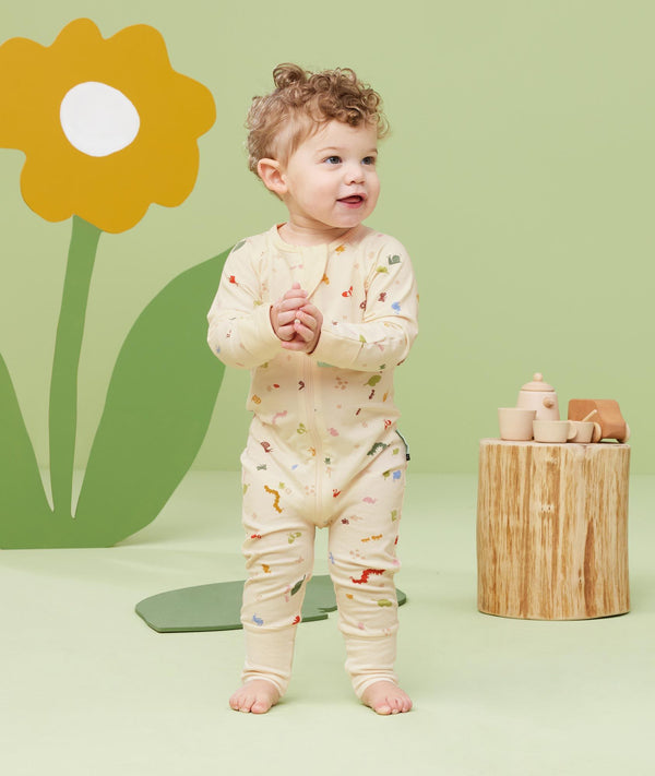 Baby standing, wearing an ergoPouch Long Sleeve Romper 0.2 TOG Critters