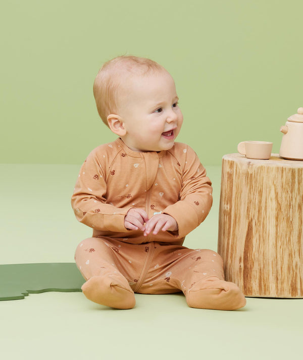Baby sitting, wearing an ergoPouch Long Sleeve Romper 0.2 TOG Honey Bees