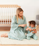Mom wearing a an ergoPouch Matchy Matchy Robe Sage, playing with a toddler in a matching color Sleep Suit Sack