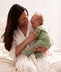 Mom wearing a an ergoPouch Matchy Matchy Robe Oatmeal Marle, holding a child