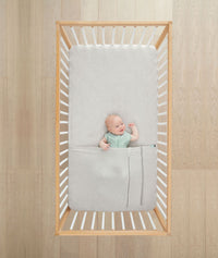 Baby asleep in a crib under a ergoPouch HugMe Blanket 0.2 & 1.0 TOG in Grey Marle