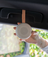ergoPouch Drift Away White Noise Machine Taupe hanging from sun visor in car