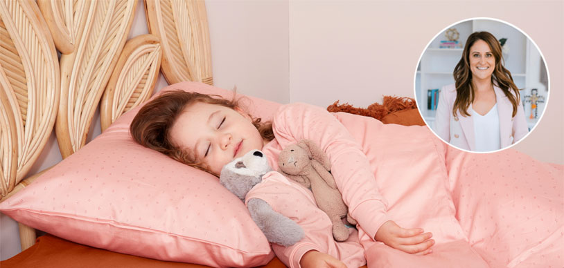 Toddler asleep in bed with pink sheets and two stuffed animals