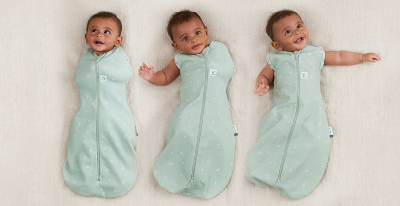 Baby transitioning from arms-in to arms-out sleeping, wearing the ergoPouch Cocoon Swaddle Sack