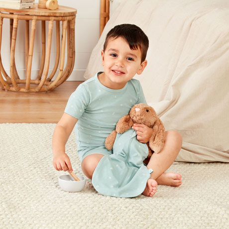Toddler sitting with teddy wearing matching PJs