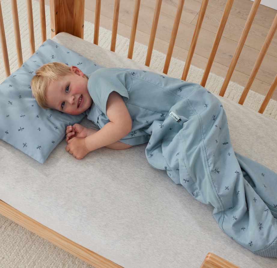toddler boy lying in cot on toddler pillow